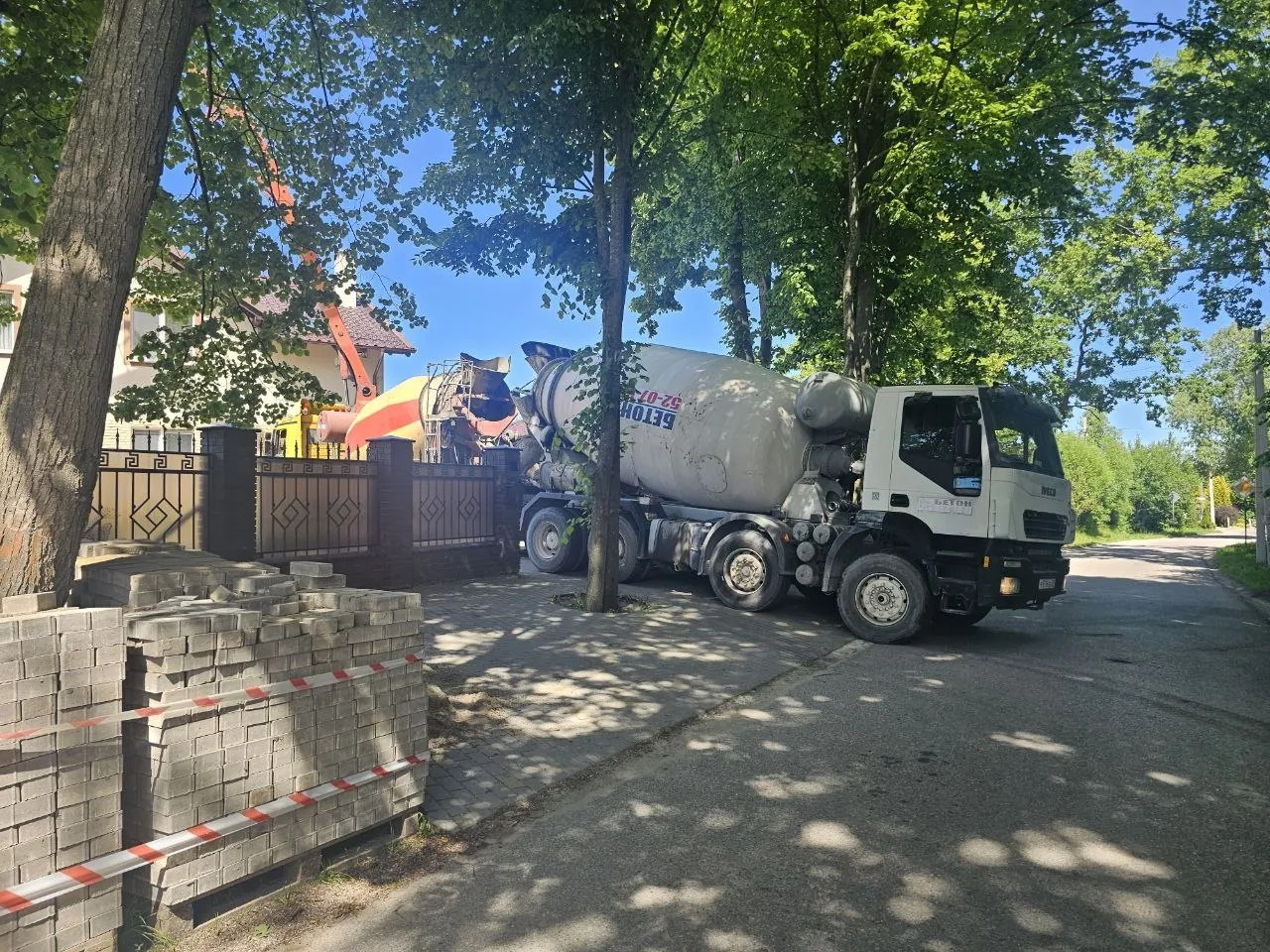 Автобетоносмеситель и насос на объекте среди деревьев